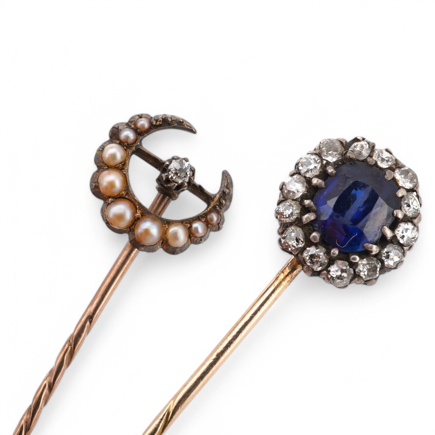 A late Victorian yellow metal, blue paste and diamond cluster set stick pin, 68mm, together with a 15ct, diamond and seed pearl set crescent stick pin. Condition - poor to fair